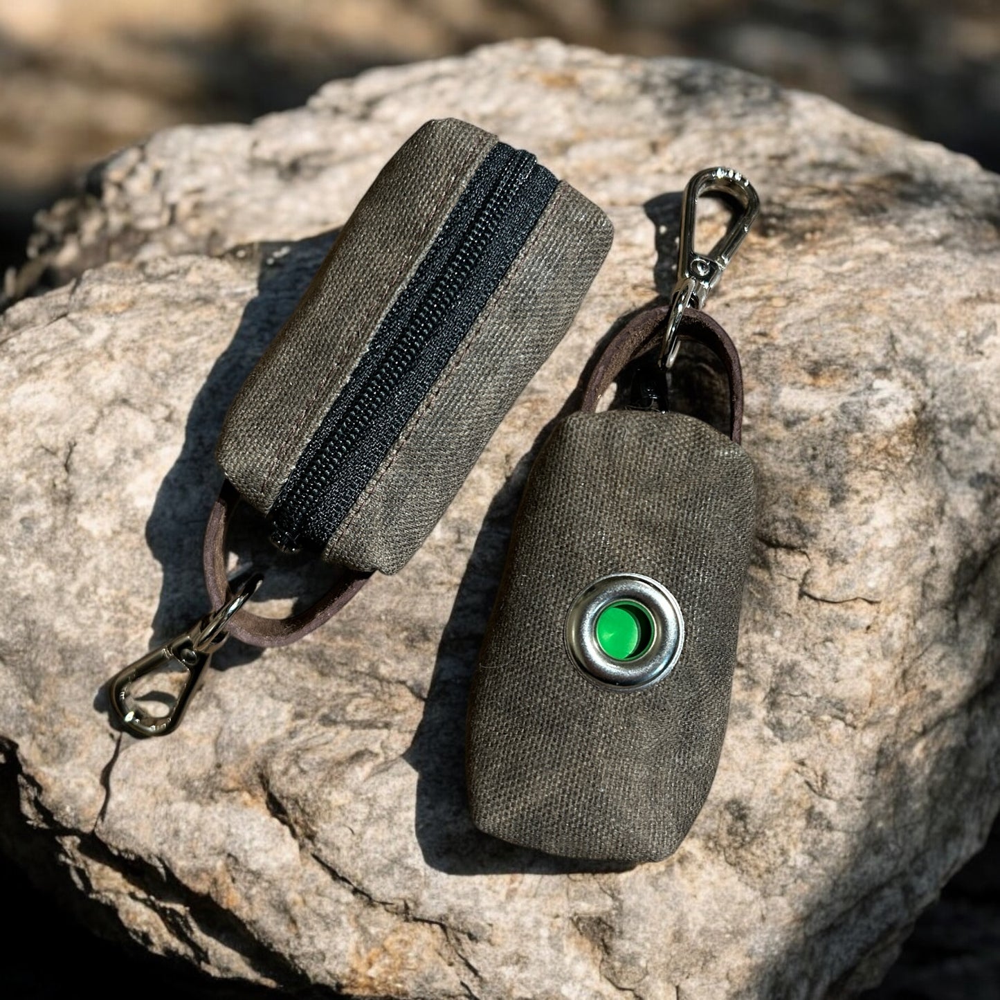 small waxed canvas dog poop bag holder with a muted brown exterior and a blue zipper, featuring a metal keychain clip and a yellow fabric loop for easy attachment. The durable, water-resistant design is ideal for carrying waste bags during dog walks. (brown, back view)
