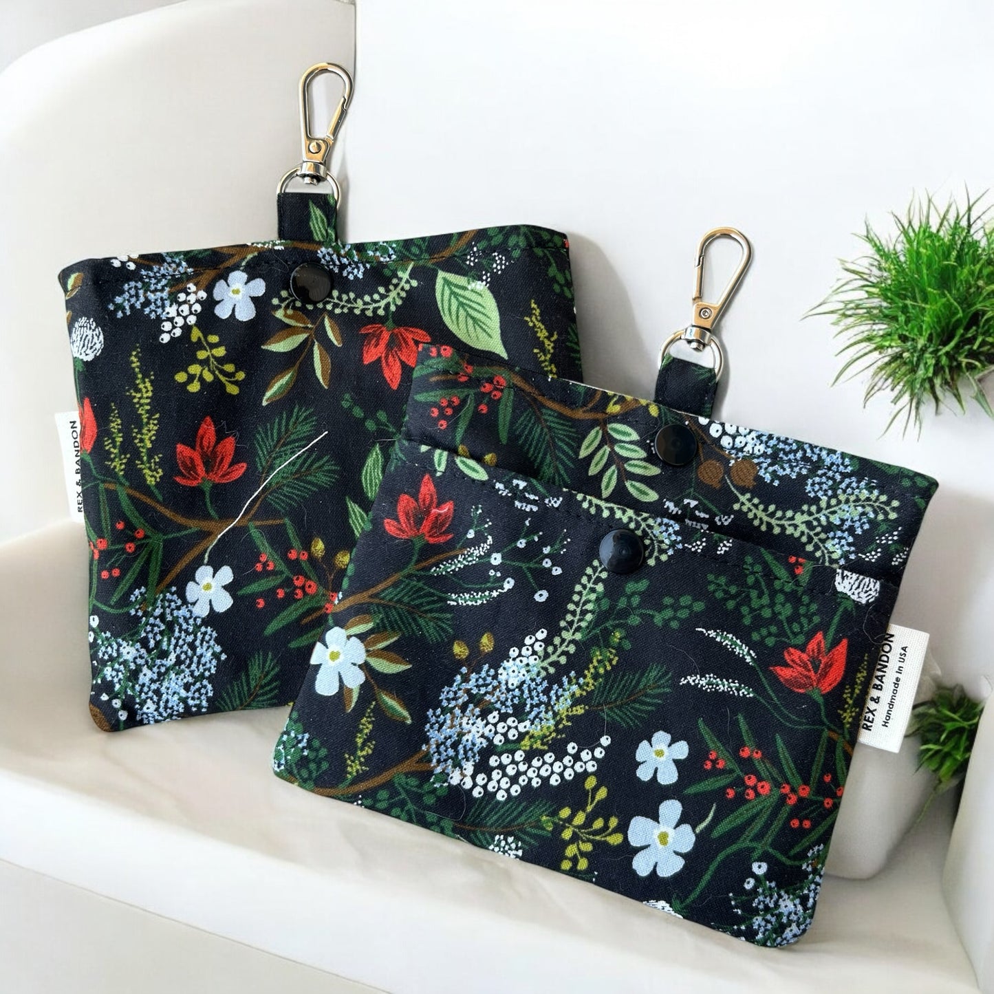 A small fabric pouch with a floral design featuring English Rose | Juniper Forest | on a black background. The pouch has a snap closure, a metal keychain clip attached to a fabric loop, and a "Handmade in USA" label.