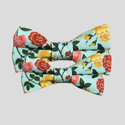 A stylish dog bow tie with a ripple pattern in mint rose floral background. The bow tie features two elastic loops on the back for attaching to a collar, displayed against a plain light background.