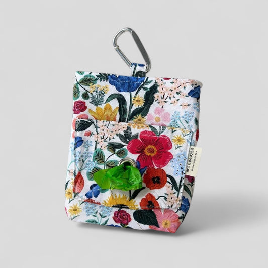 Floral-patterned pouch with carabiner and green poop bag refill on a light gray background
