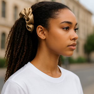 Woman with braided hair wearing a gold scrunchie, standing outdoors.
