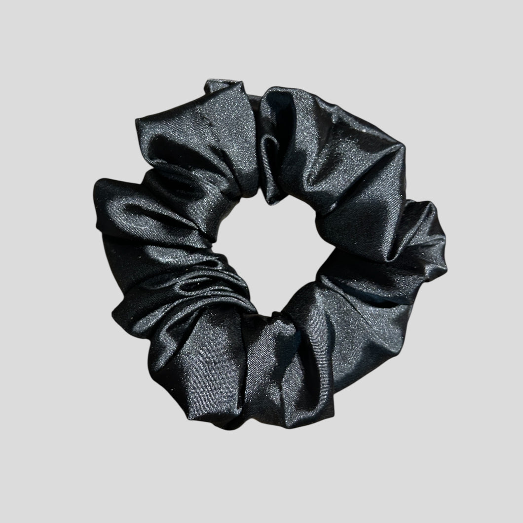 Black glittery scrunchie on a light gray background