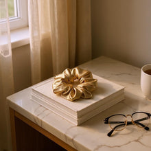 Load image into Gallery viewer, Gold scrunchie on a stack of books with glasses and a cup on a marble surface.