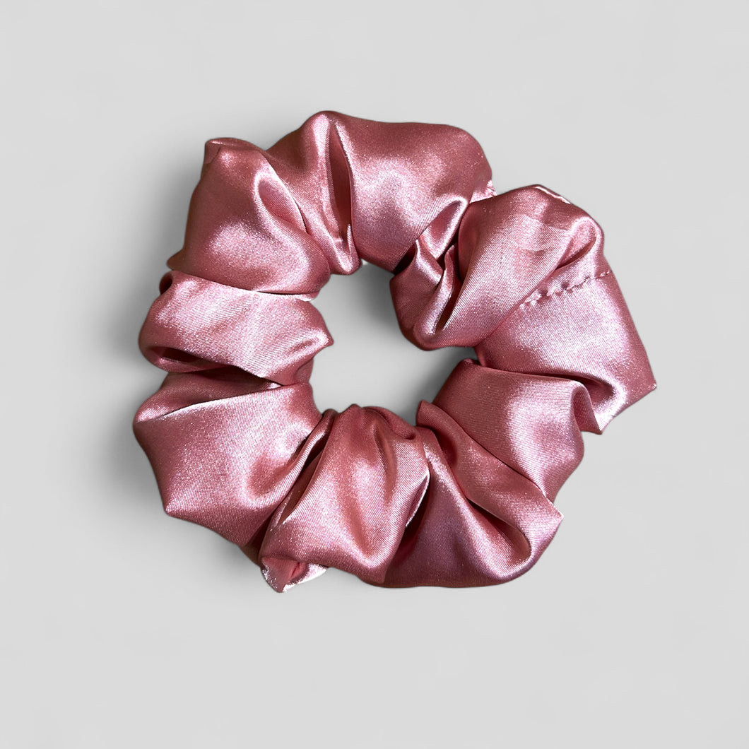 Pink satin scrunchie on a light gray background