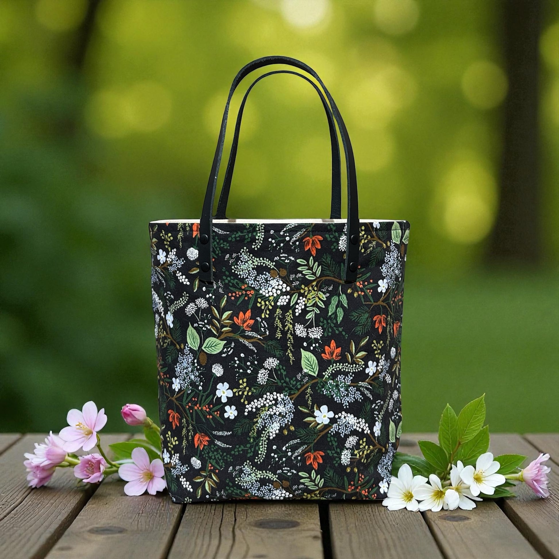 Floral-patterned tote bag on a wooden surface with flowers, against a blurred green natural background