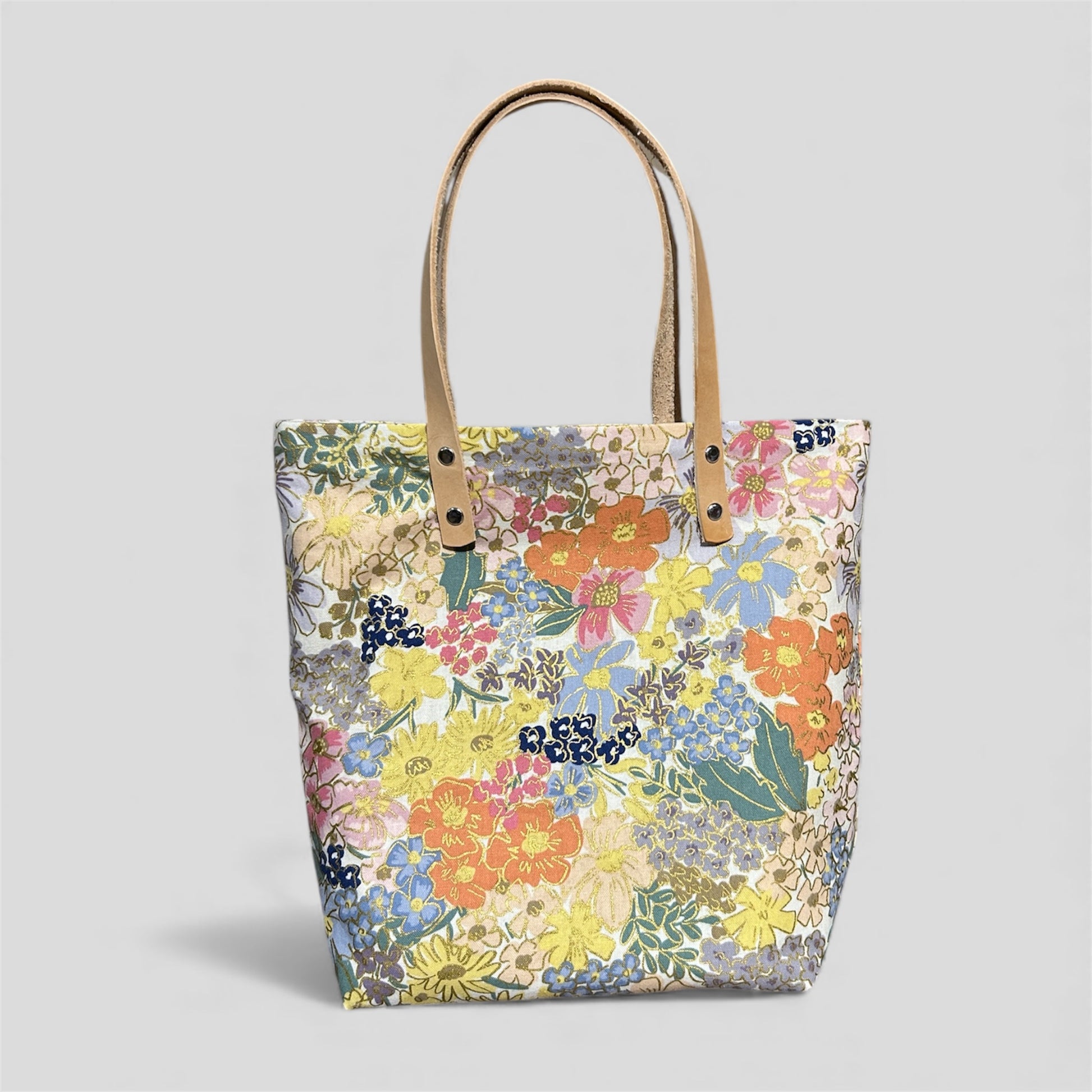 Floral tote bag with brown handles on a light gray background