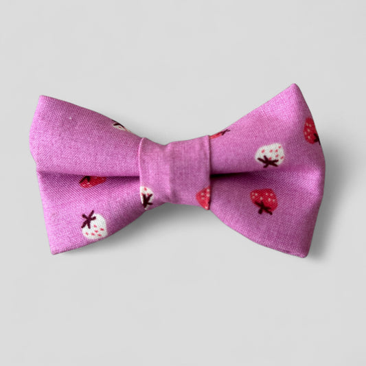 Pink bow tie with strawberry pattern on a light gray background