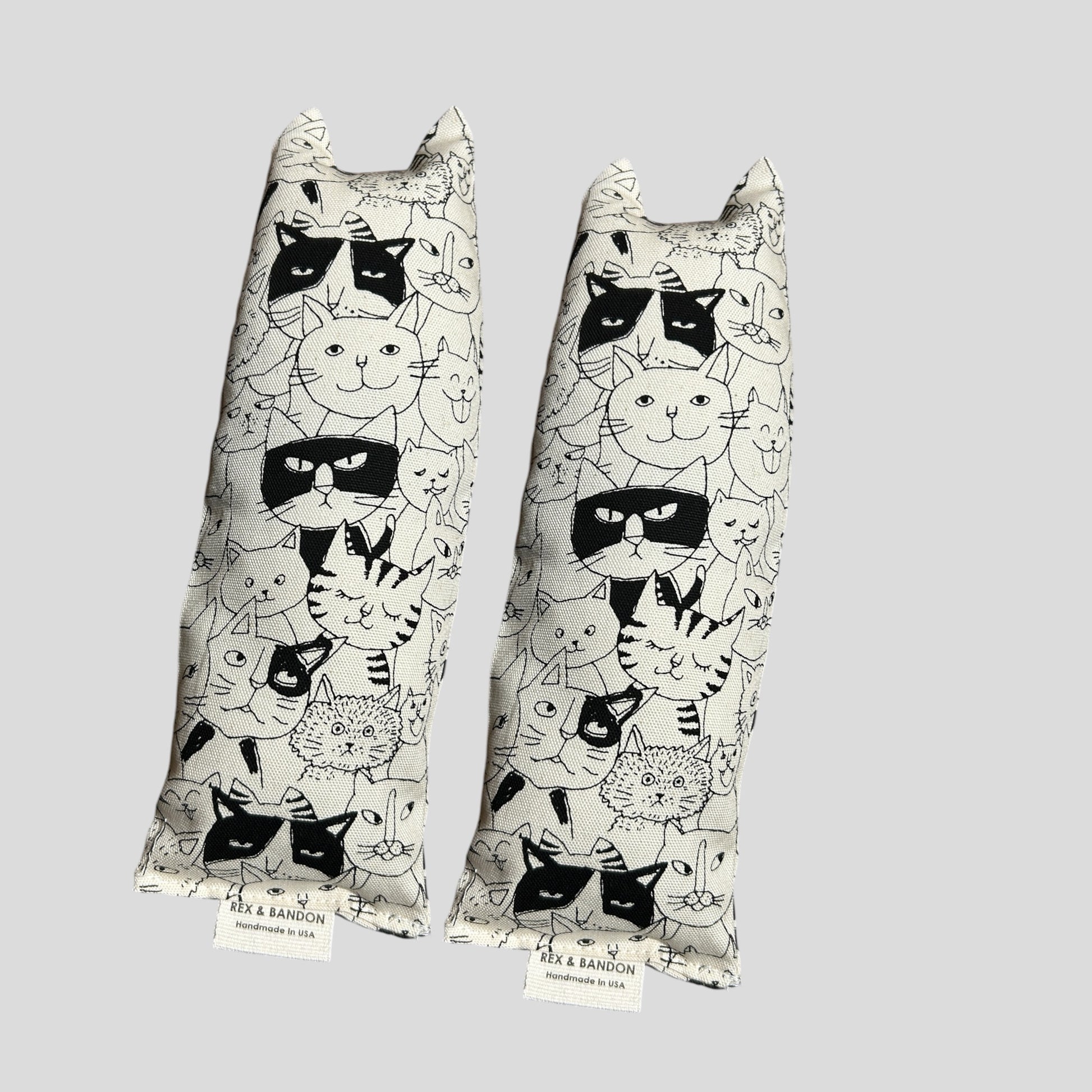 Two cat-shaped pillows with black and white cat patterns on a light gray background.