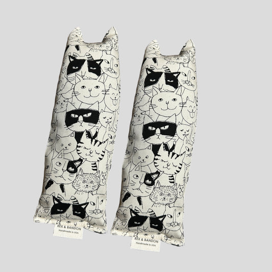 Two cat-shaped pillows with black and white cat patterns on a light gray background.