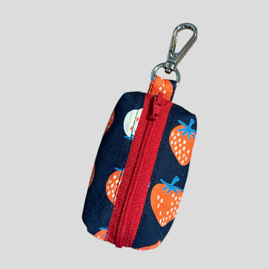 Keychain pouch with strawberry pattern and red zipper on a gray background