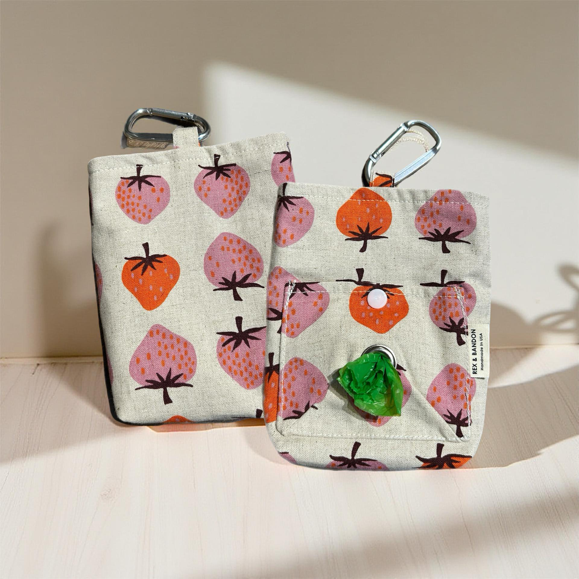 Two fabric pouches with strawberry pattern on a beige background