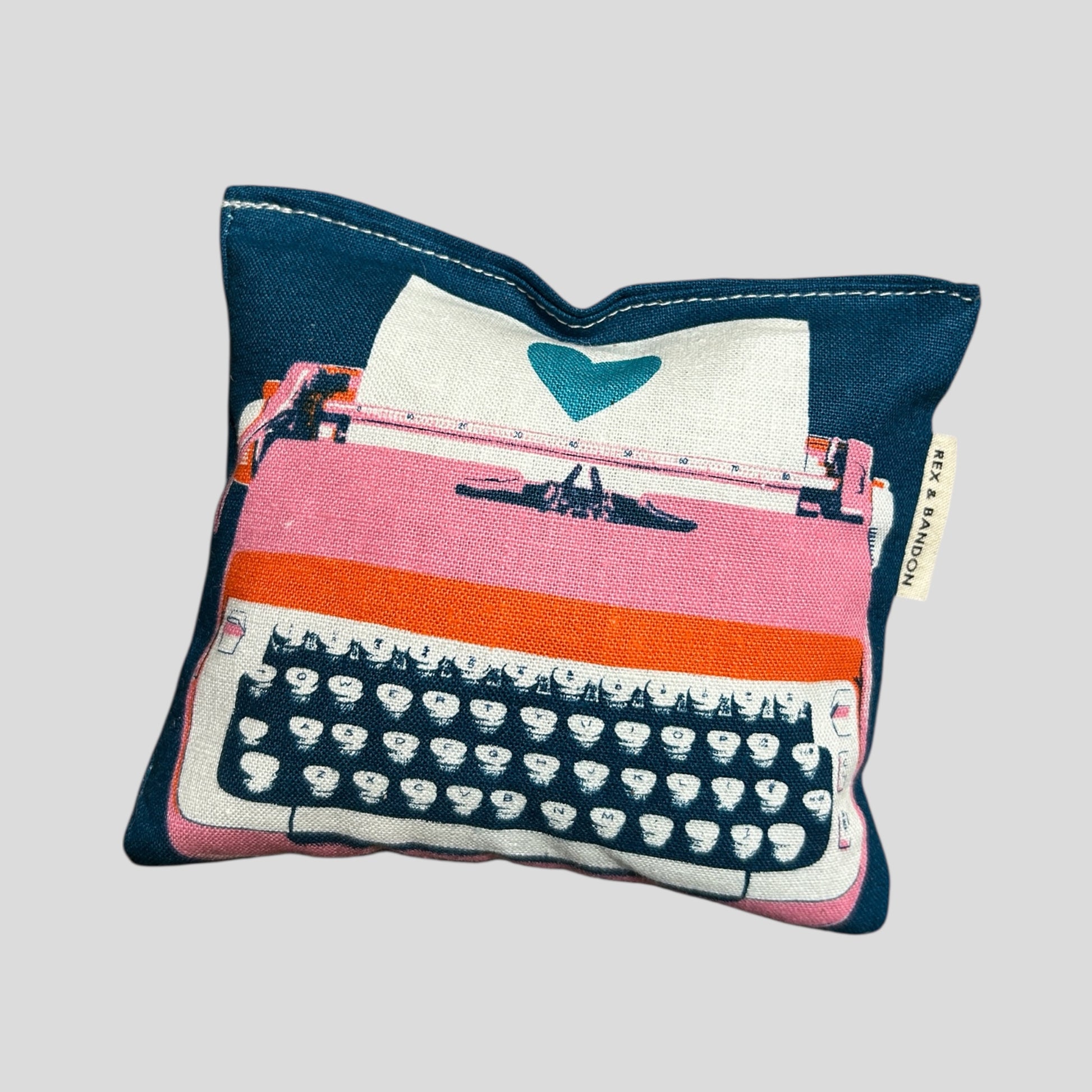 A close-up of a large square catnip pouch toy on a clean white background. The pouch is crafted from durable cotton fabric in a modern vintage typewriter print with vibrant colors. It measures approximately 5.5 x 5 inches, plumply stuffed with potent organic catnip and features a hidden crinkle nose inside for added sound play. Simple, sturdy stitching along the edges ensures long-lasting fun for kicking, wrestling, and cuddling. Handmade with love.