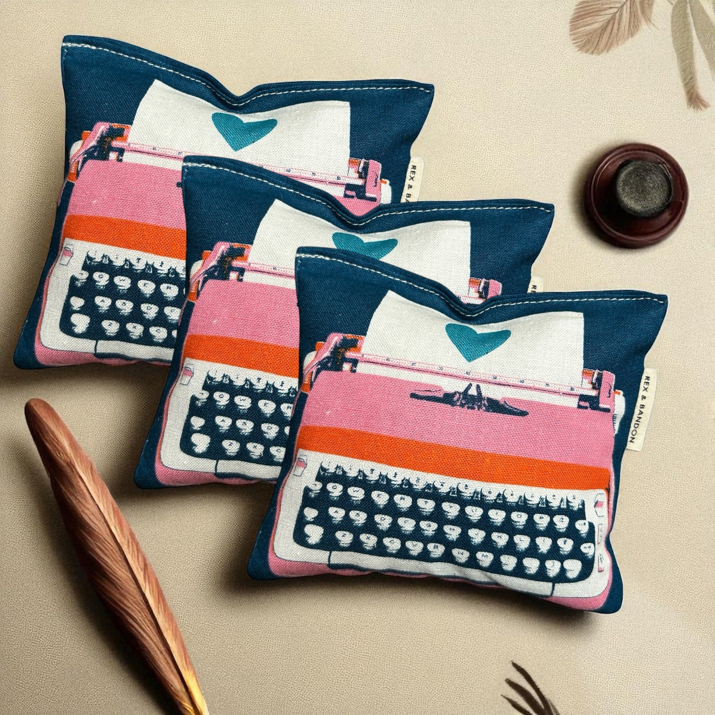 A close-up of a large square catnip pouch toy on a clean white background. The pouch is crafted from durable cotton fabric in a modern vintage typewriter print with vibrant colors. It measures approximately 5.5 x 5 inches, plumply stuffed with potent organic catnip and features a hidden crinkle nose inside for added sound play. Simple, sturdy stitching along the edges ensures long-lasting fun for kicking, wrestling, and cuddling. Handmade with love.