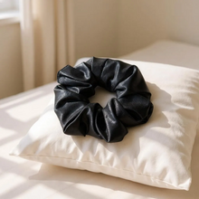 Load image into Gallery viewer, Black satin scrunchie on a white pillow with soft lighting