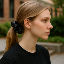 Load image into Gallery viewer, Woman with a black scrunchie in her hair, wearing a black shirt, outdoors.