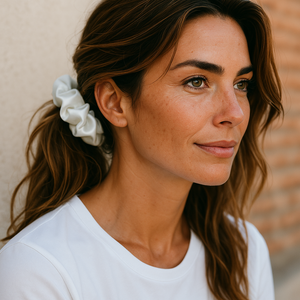 Woman with a white scrunchie in her hair against a neutral background
