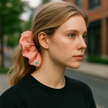 Load image into Gallery viewer, Woman with a red checkered scrunchie in her hair, wearing a black shirt, outdoors.